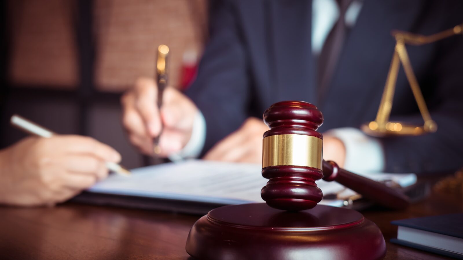 Documents being signed beside a gavel and scales
