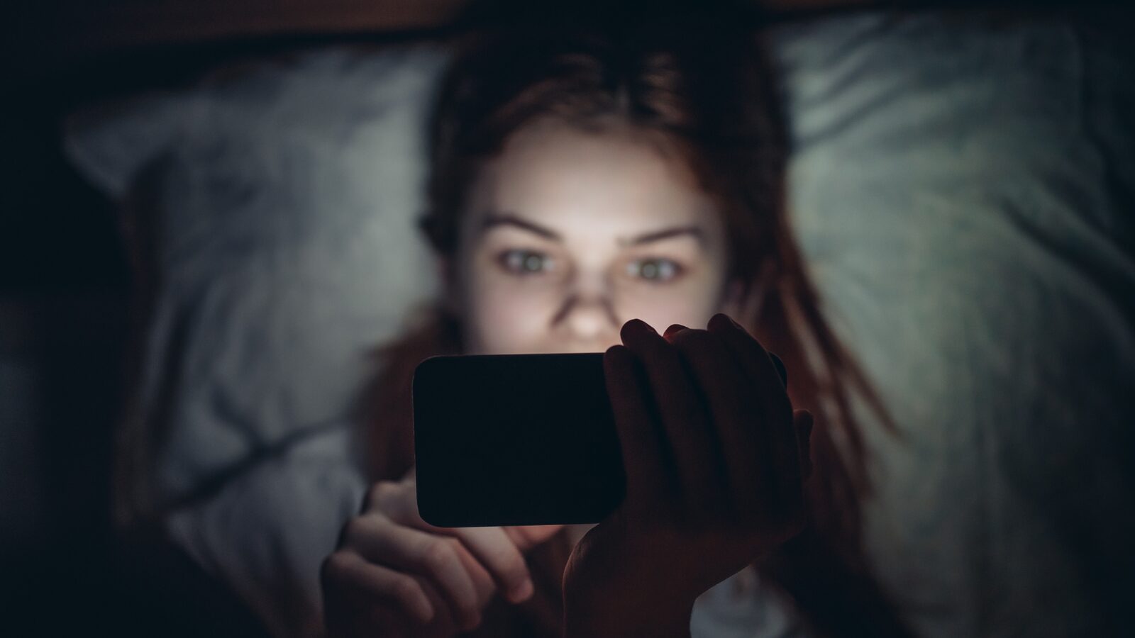 A person reading a phone in the dark