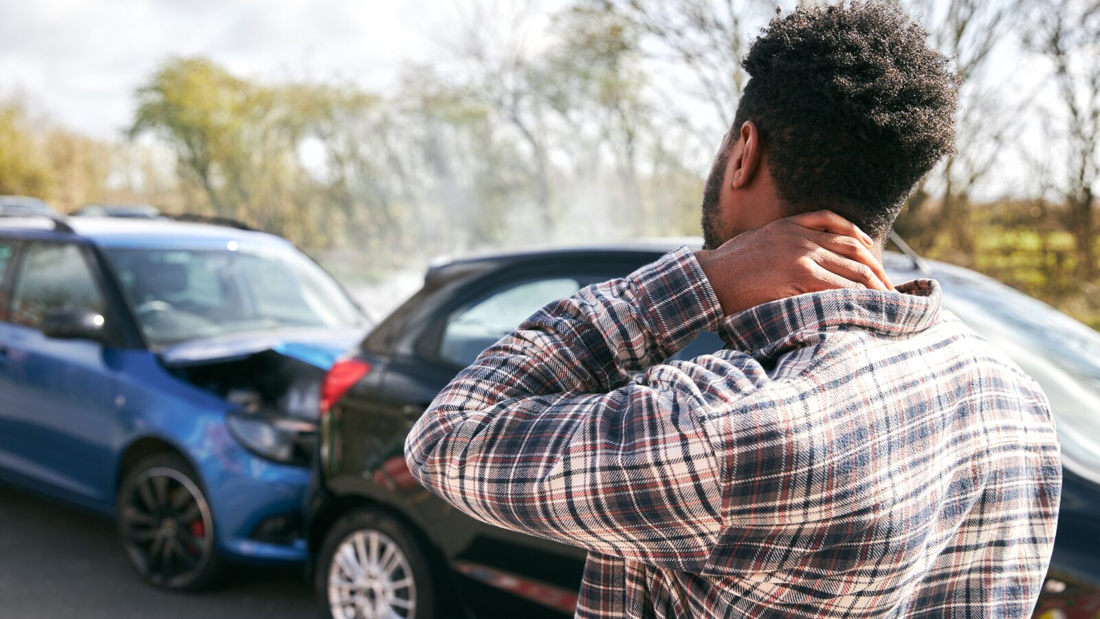 A driver holding his neck at the roadside after a collision